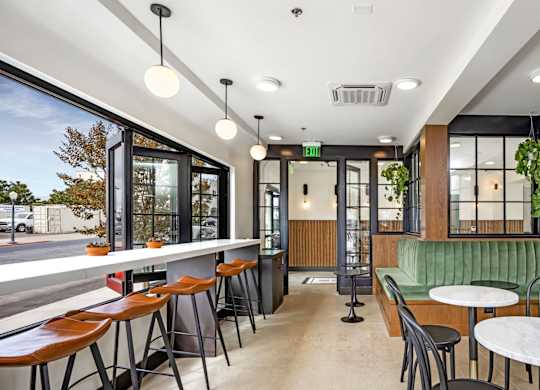 A modern restaurant with a green booth and wooden tables.