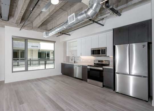 A kitchen with stainless steel appliances and wooden floors.