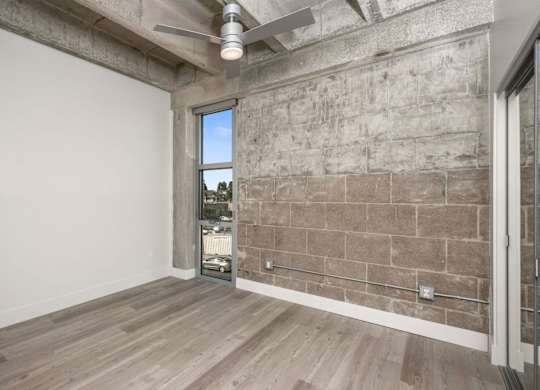 A room with a ceiling fan and a window overlooking a cityscape.