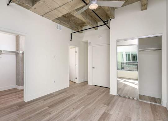 A room with wooden floors and white walls, with a doorway leading to another room.