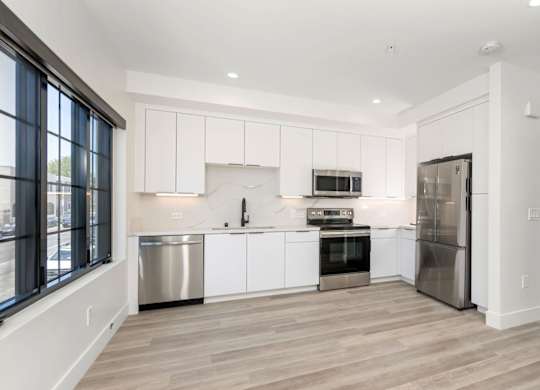 A modern kitchen with white cabinets and stainless steel appliances.