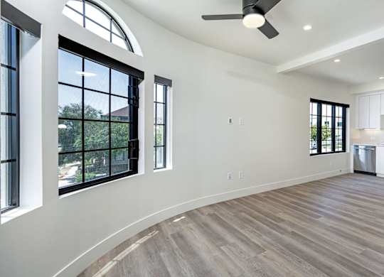 A spacious kitchen with a fan and a view of trees through the windows.