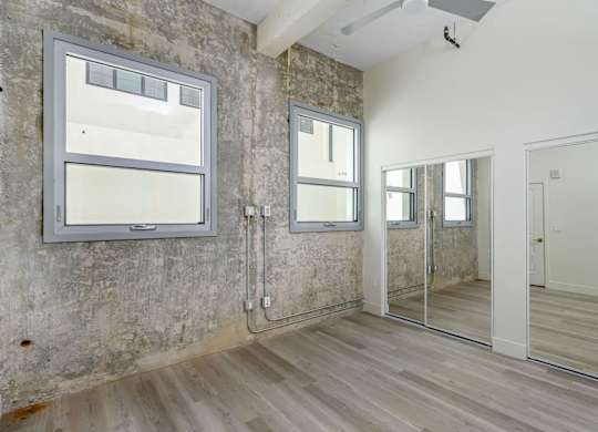 A room with a white door, a mirror, and a window.