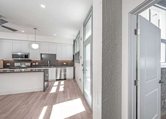 A modern kitchen with a white door and a wall with pipes.