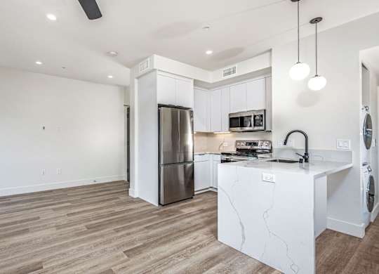 A modern kitchen with a refrigerator, microwave, and oven.