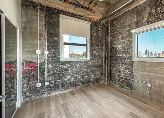 A room with a window showing a cityscape and a wooden floor.