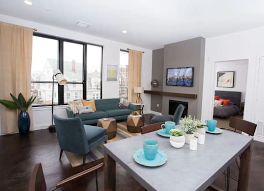 A modern living room with a grey dining table and blue chairs.