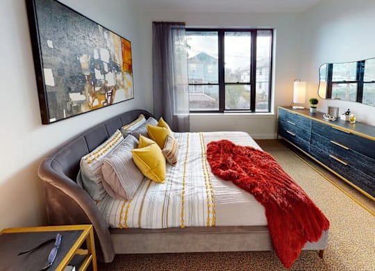 A bedroom with a bed, a nightstand, and a painting on the wall.