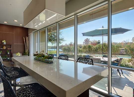 A modern kitchen with a long counter and chairs.