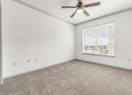 A room with a ceiling fan and a window with blinds.