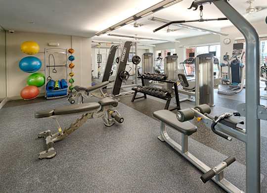 A gym with a variety of equipment including weights and exercise balls.