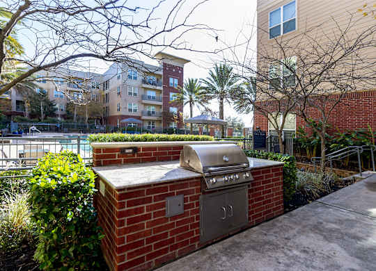 A brick barbecue grill is in the foreground of a residential area.