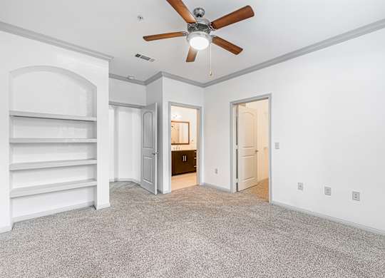 A room with a ceiling fan and carpeted floor.
