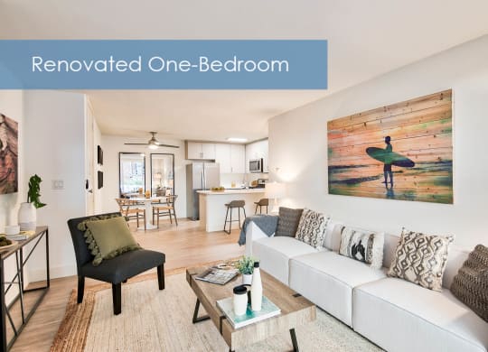 a renovated one bedroom living room with a white couch and a surfboard at The Meadows Apartments, Culver City , CA 90230
