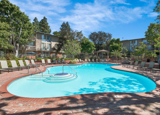 a resort style pool with chairs and a building in the background at The Meadows Apartments, Culver City , California