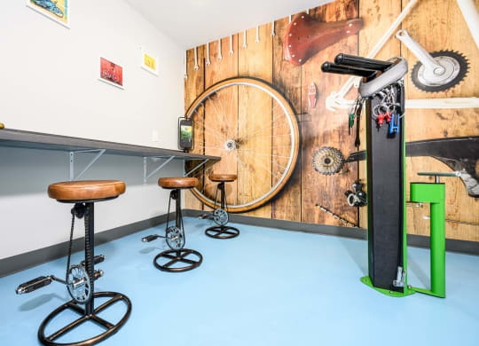 a bike room with stools and a bike wheel on a wall at Sendero Huntington Beach, Huntington Beach