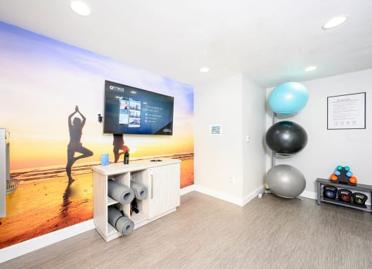 a yoga room with a large screen tv and a yoga ball at Sendero Huntington Beach, Huntington Beach