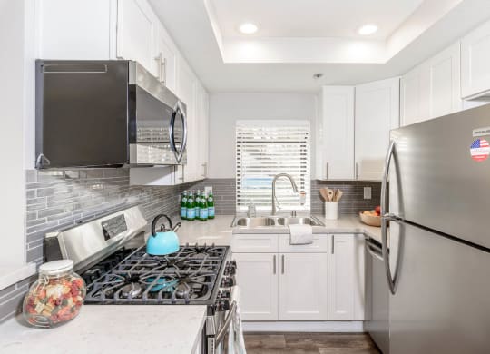 a small kitchen with stainless steel appliances and white cabinets at Sendero Huntington Beach, California