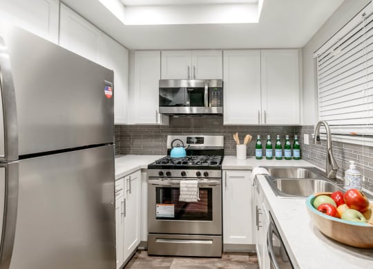 A kitchen with stainless steel appliances and white cabinets at Sendero Huntington Beach, Huntington Beach California