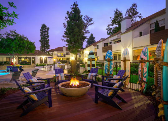 a patio with a fire pit and chairs at night at Sendero Huntington Beach, California