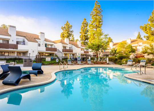 a swimming pool with lounge chairs and buildings in the background at Sendero Huntington Beach, Huntington Beach California