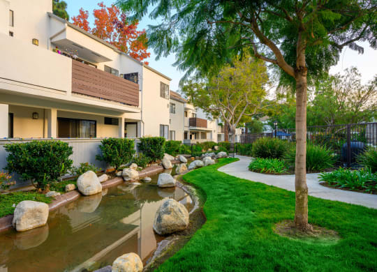 a building with a stream and rocks in the grass at Sendero Huntington Beach, Huntington Beach, CA