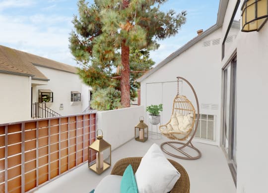 a patio with a swing and a chair on a balcony at Sendero Huntington Beach, California