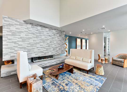 A modern living room with a stone fireplace and a blue rug. at Esprit Apartments, Marina del Rey