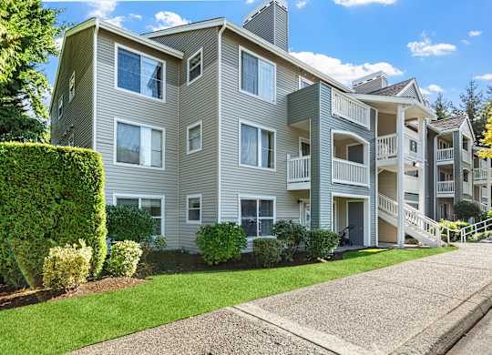 A large apartment building with a well-maintained lawn in front.