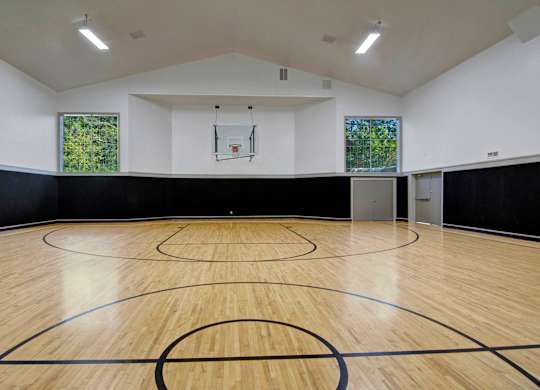 A basketball court with a wooden floor and a basketball hoop.