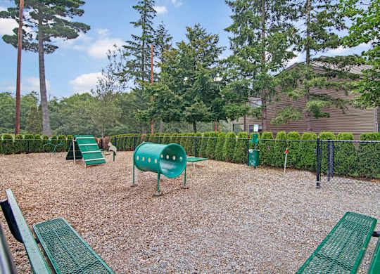 A playground with green equipment and a gravel ground.