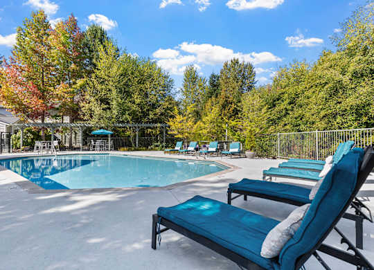 Resort-style outdoor pool with lounge chairs and landscaped surroundings.