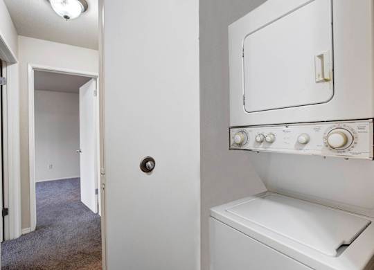 Laundry closet with a stacked washer and dryer beside the hallway.