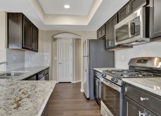 a kitchen with stainless steel appliances and marble counter tops  at San Montego Apartments, Mesa, AZ