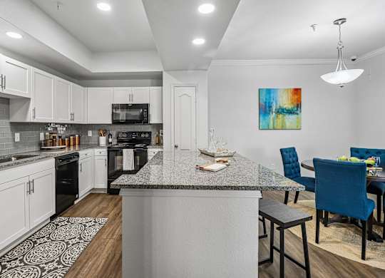 A kitchen with a large island and a dining area with blue chairs.