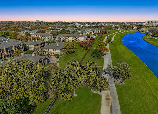 A river flows through a green park with apartment buildings in the background  at The Canyons Apartments, Texas, 76116