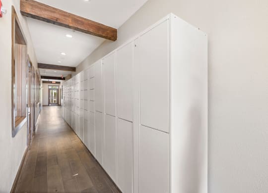 a long row of white cabinets in a hallway with wood floors at Lakeline East Apartments, Cedar Park, 78613