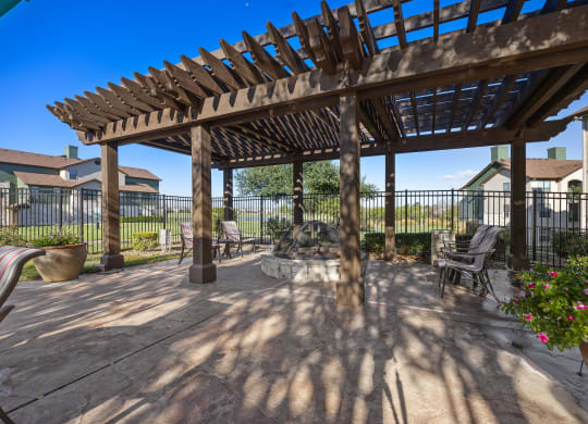 a patio with a wooden pergola and a fire pit at The Fairways at Star Ranch, Texas