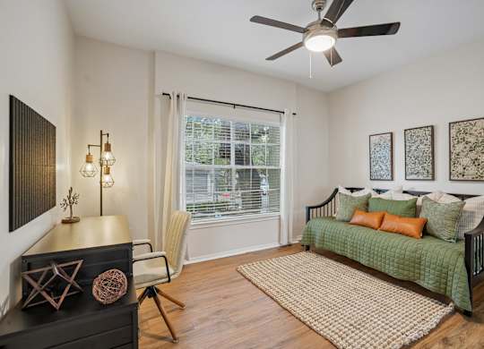 A room with a green sofa and a fan on the ceiling.