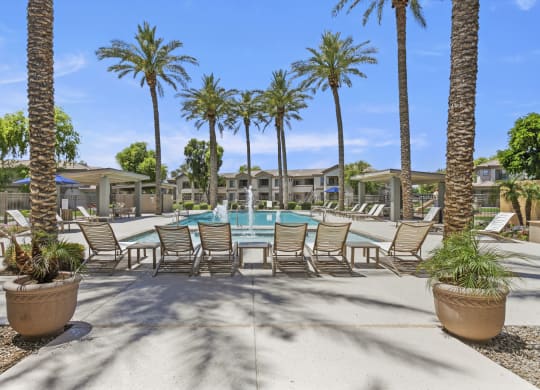 a swimming pool with chaise lounge chairs and palm trees at Adiamo Palm Valley, Goodyear, AZ