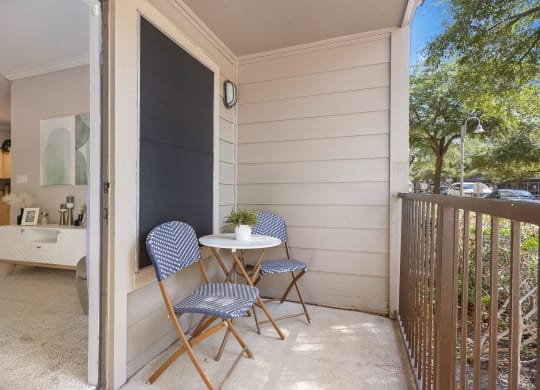 a small table and two chairs sit on a balcony in front of a kitchen at Artisan Apartments & Shops, Texas, 78729