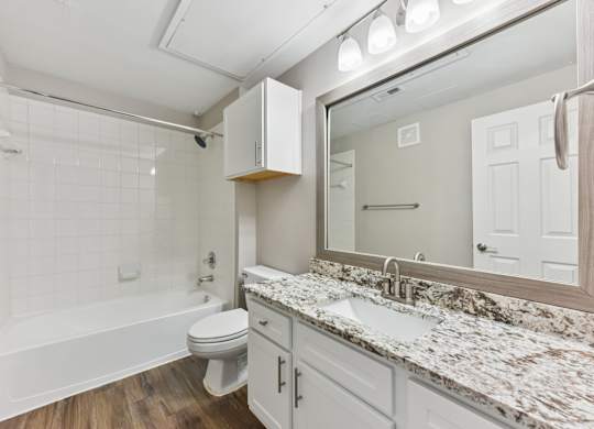 A white bathroom with a marble countertop and a white bathtub. at Sonterra Apartment Homes, Austin