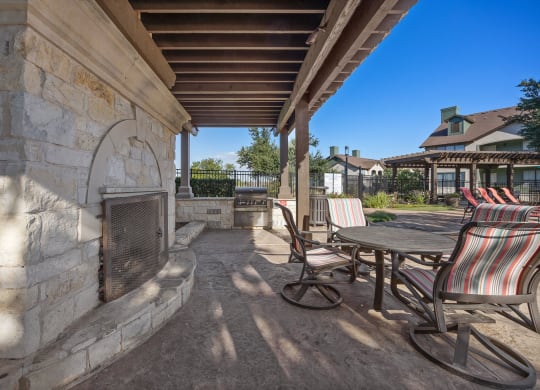 a covered patio with chairs and a table and a fireplace at The Fairways at Star Ranch, Hutto