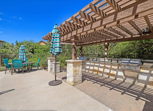 a patio with a pergola and table with umbrellas at Lakeline East Apartments, Cedar Park
