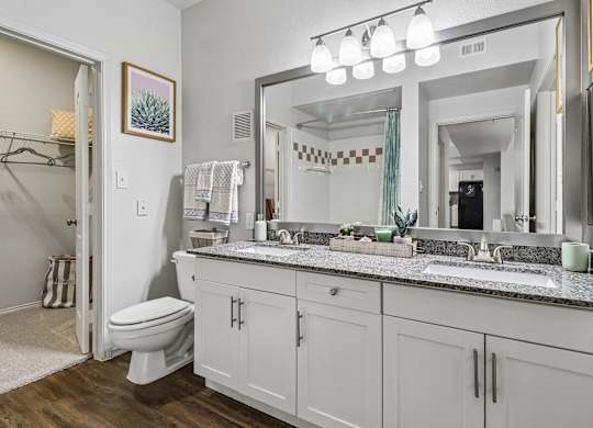 A bathroom with a toilet, sink, and mirror.