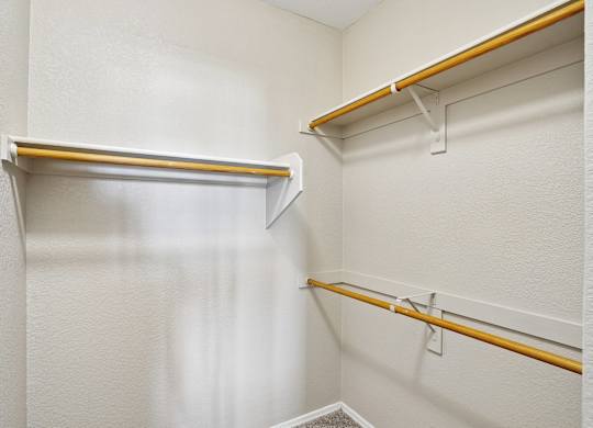 A white closet with two shelves and a white door.