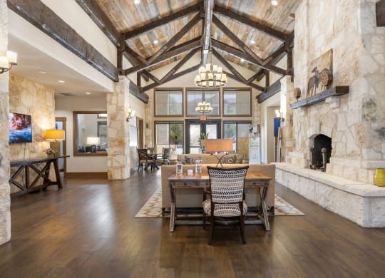 a dining room with a table and chairs in front of a stone fireplace at Lakeline East Apartments, Cedar Park