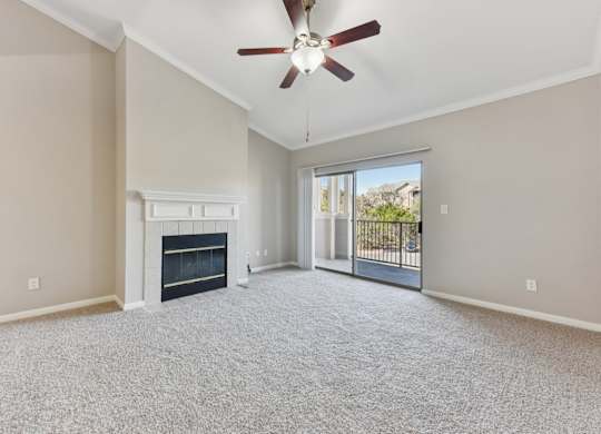 A spacious living room with a fireplace and a ceiling fan. at Sonterra Apartment Homes, Austin, TX, 78726