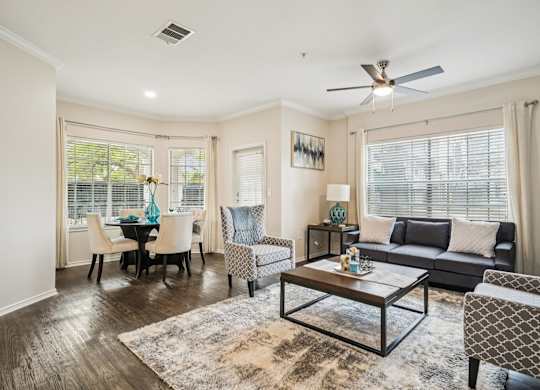 A living room with a black couch, a coffee table, and a dining table with chairs.