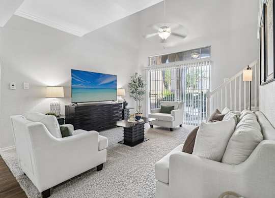 A living room with a white couch and a painting of a beach scene on the wall.